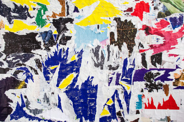 Street billboard with old dirty torn and peeling paper posters texture background.