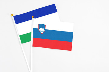 Slovenia and Lesotho stick flags on white background. High quality fabric, miniature national flag. Peaceful global concept.White floor for copy space.