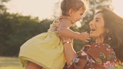 Satisfied indian woman enjoys the moment with her happy child girl and whirling her in park outdoors