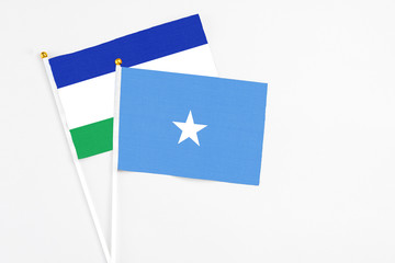 Somalia and Lesotho stick flags on white background. High quality fabric, miniature national flag. Peaceful global concept.White floor for copy space.