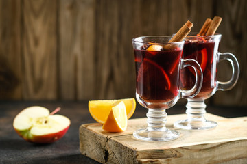 Mulled wine in glass glasses with apples, orange, cinnamon and star anise. Hot christmas drink on dark background with spruce branch.