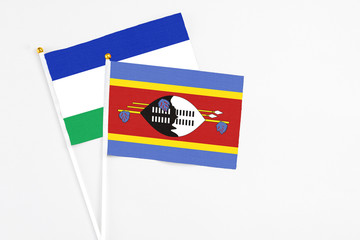 Swaziland and Lesotho stick flags on white background. High quality fabric, miniature national flag. Peaceful global concept.White floor for copy space.