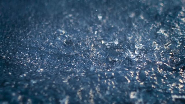 Slow-motion close-up shot of a running shoe going through a puddle of water in the rain creating a splash