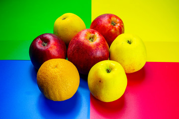fresh fruits, red and green apples and oranges on a colored background
