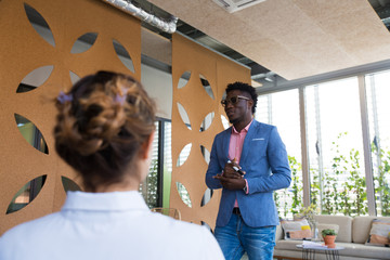 Positive successful coach performing before audience. Stylish African American business man holding...