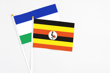 Uganda and Lesotho stick flags on white background. High quality fabric, miniature national flag....