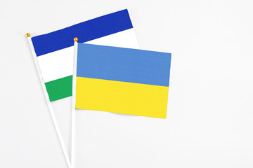 Ukraine and Lesotho stick flags on white background. High quality fabric, miniature national flag. Peaceful global concept.White floor for copy space.