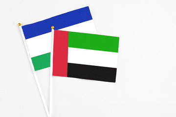 United Arab Emirates and Lesotho stick flags on white background. High quality fabric, miniature national flag. Peaceful global concept.White floor for copy space.