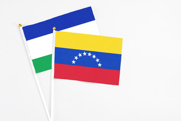 Venezuela and Lesotho stick flags on white background. High quality fabric, miniature national flag. Peaceful global concept.White floor for copy space.