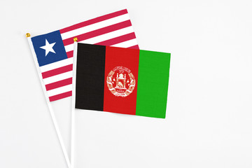 Afghanistan and Liberia stick flags on white background. High quality fabric, miniature national flag. Peaceful global concept.White floor for copy space.