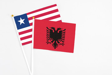 Albania and Liberia stick flags on white background. High quality fabric, miniature national flag. Peaceful global concept.White floor for copy space.