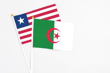 Algeria and Liberia stick flags on white background. High quality fabric, miniature national flag. Peaceful global concept.White floor for copy space.