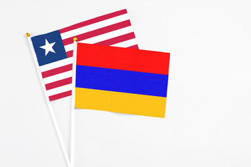 Armenia and Liberia stick flags on white background. High quality fabric, miniature national flag. Peaceful global concept.White floor for copy space.