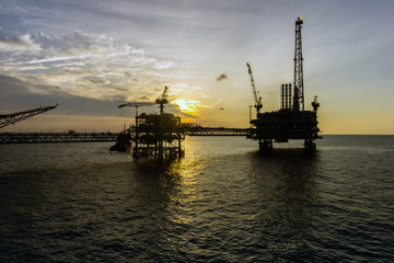 Fototapeta na wymiar Silhouette of oil production platform during sunset at oil field