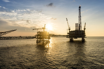 Fototapeta na wymiar Silhouette of oil production platform during sunset at oil field