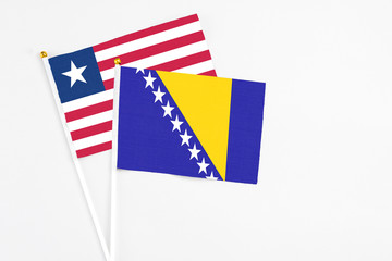 Bosnia Herzegovina and Liberia stick flags on white background. High quality fabric, miniature national flag. Peaceful global concept.White floor for copy space.