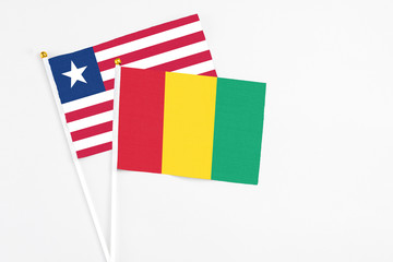 Guinea and Liberia stick flags on white background. High quality fabric, miniature national flag. Peaceful global concept.White floor for copy space.