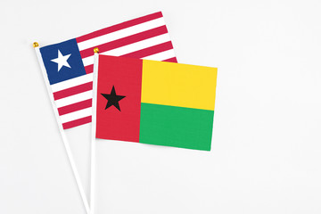 Fototapeta premium Guinea Bissau and Liberia stick flags on white background. High quality fabric, miniature national flag. Peaceful global concept.White floor for copy space.