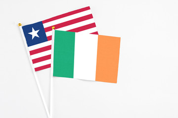 Ireland and Liberia stick flags on white background. High quality fabric, miniature national flag. Peaceful global concept.White floor for copy space.