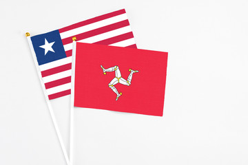 Isle Of Man and Liberia stick flags on white background. High quality fabric, miniature national flag. Peaceful global concept.White floor for copy space.