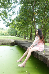 Portrait of young asian woman sitting on wooden bridge