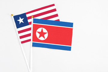 North Korea and Liberia stick flags on white background. High quality fabric, miniature national flag. Peaceful global concept.White floor for copy space.