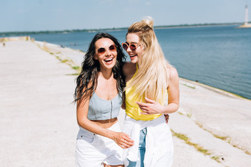 happy laughing girls walking near river in summer