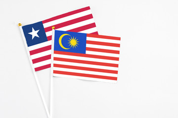 Malaysia and Liberia stick flags on white background. High quality fabric, miniature national flag. Peaceful global concept.White floor for copy space.