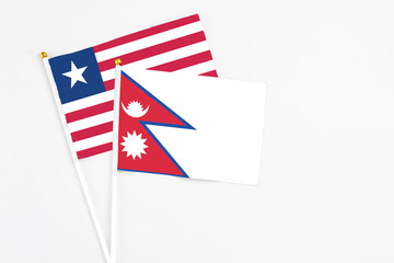 Nepal and Liberia stick flags on white background. High quality fabric, miniature national flag. Peaceful global concept.White floor for copy space.