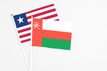 Oman and Liberia stick flags on white background. High quality fabric, miniature national flag. Peaceful global concept.White floor for copy space.