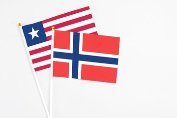 Obraz premium Norway and Liberia stick flags on white background. High quality fabric, miniature national flag. Peaceful global concept.White floor for copy space.