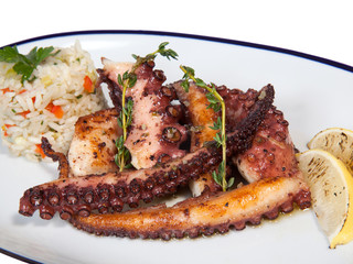 Grilled seafood octopus with rice and lemon on white oval plate