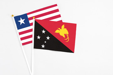 Papua New Guinea and Liberia stick flags on white background. High quality fabric, miniature national flag. Peaceful global concept.White floor for copy space.
