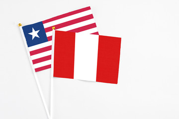 Peru and Liberia stick flags on white background. High quality fabric, miniature national flag. Peaceful global concept.White floor for copy space.