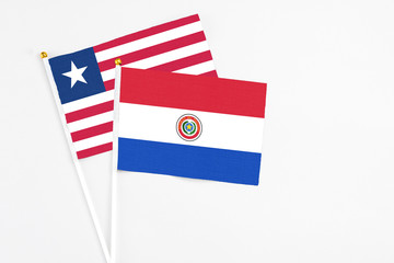 Paraguay and Liberia stick flags on white background. High quality fabric, miniature national flag. Peaceful global concept.White floor for copy space.