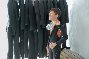 boy measures the diving suit and looks into the distance