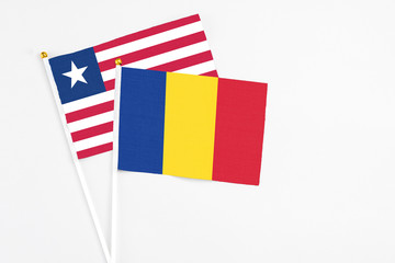 Romania and Liberia stick flags on white background. High quality fabric, miniature national flag. Peaceful global concept.White floor for copy space.