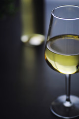 Transparent bottle of white dry wine on the table. White wine glass on a wooden background.