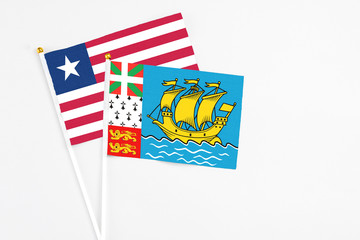 Saint Pierre And Miquelon and Liberia stick flags on white background. High quality fabric, miniature national flag. Peaceful global concept.White floor for copy space.