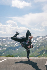 A motorcycle traveler arrived at his destination and dance wiht happines. Conquering the top of the mountain, Grossglockner pass, biker dressed in a protective jacket armor of the body. Austria