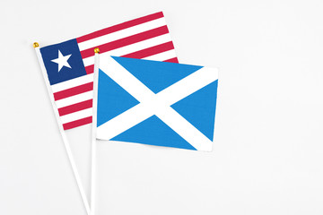 Scotland and Liberia stick flags on white background. High quality fabric, miniature national flag. Peaceful global concept.White floor for copy space.