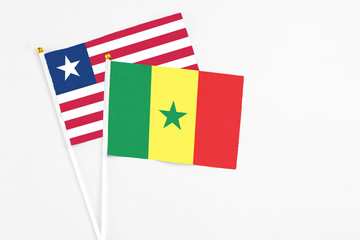 Senegal and Liberia stick flags on white background. High quality fabric, miniature national flag. Peaceful global concept.White floor for copy space.