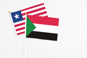 Sudan and Liberia stick flags on white background. High quality fabric, miniature national flag. Peaceful global concept.White floor for copy space.