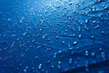Water drops on waterproof nylon fabric. Macro detail view of texture of blue woven synthetic waterproof clothing. morning dew on camping tent close view. Rain