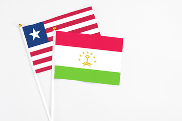 Tajikistan and Liberia stick flags on white background. High quality fabric, miniature national flag. Peaceful global concept.White floor for copy space.