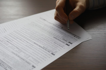 Business meeting. A man signs a contract. Male hand with pen makes notes in the office.