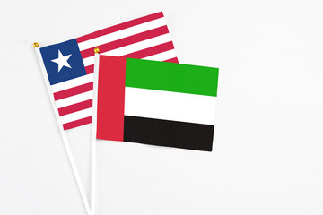 United Arab Emirates and Liberia stick flags on white background. High quality fabric, miniature national flag. Peaceful global concept.White floor for copy space.