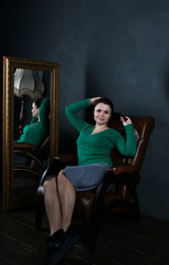 girl in green in a brown armchair