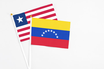 Venezuela and Liberia stick flags on white background. High quality fabric, miniature national flag. Peaceful global concept.White floor for copy space.