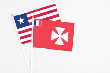 Wallis And Futuna and Liberia stick flags on white background. High quality fabric, miniature...